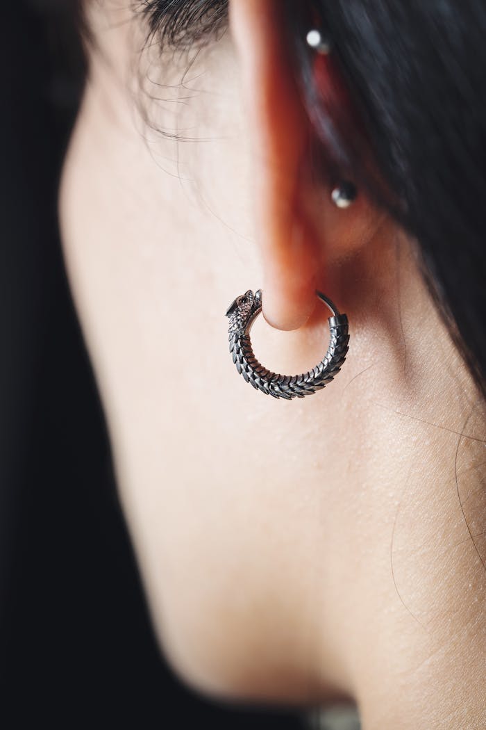 Close-up of a stylish silver hoop earring on a person’s ear, showcasing modern jewelry design.