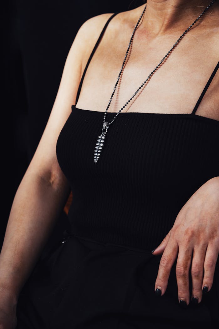 Close-up of a woman in black attire with a silver dragon pendant necklace.
